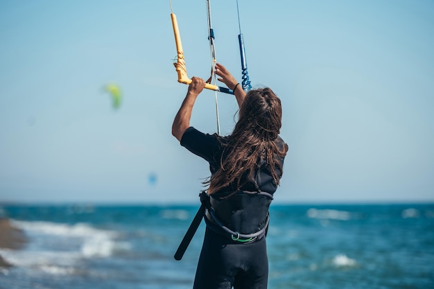 Junge sportliche Frau mit Steuerstange, um ihren Kite zum Kitesurfen anzuheben