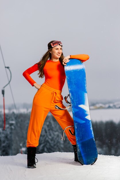Junge sportliche lächelnde Frau im Winter mit Snowboard, Brille