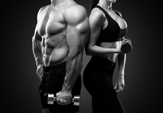Junge sportliche Paare, die auf schwarzem Hintergrund aufwerfen. Schwarzweißfoto