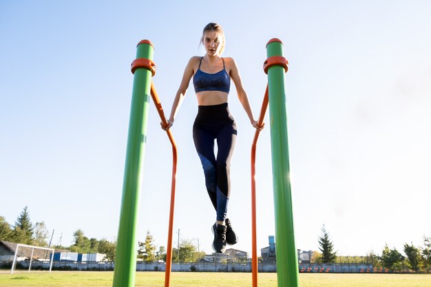 Junge sportliche Sportlerin, die auf Metallstangen ausübt