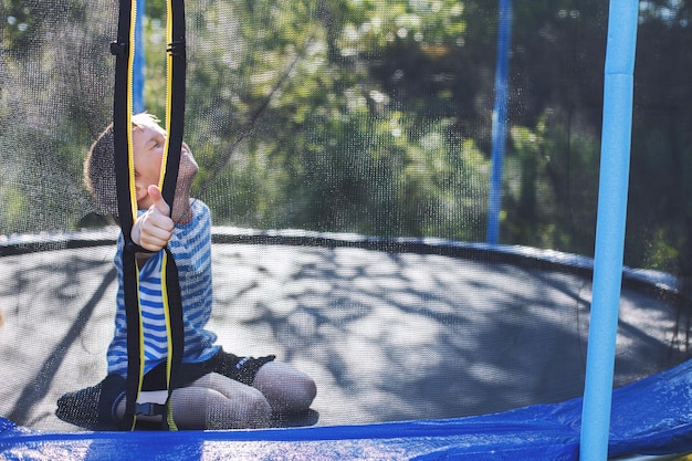 Junge springt auf Trampolin Kind spielt und zeigt Daumen hoch