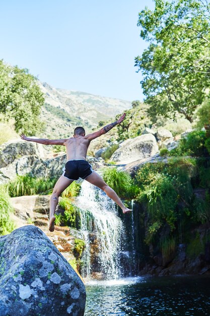 Junge springt ins Wasser des natürlichen Pools mit Wasserfall.