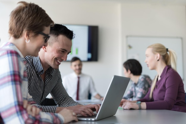 junge Startup-Geschäftsleute, Paare, die an Laptop-Computern arbeiten, Geschäftsleute treffen sich im Hintergrund im Bürointerieur