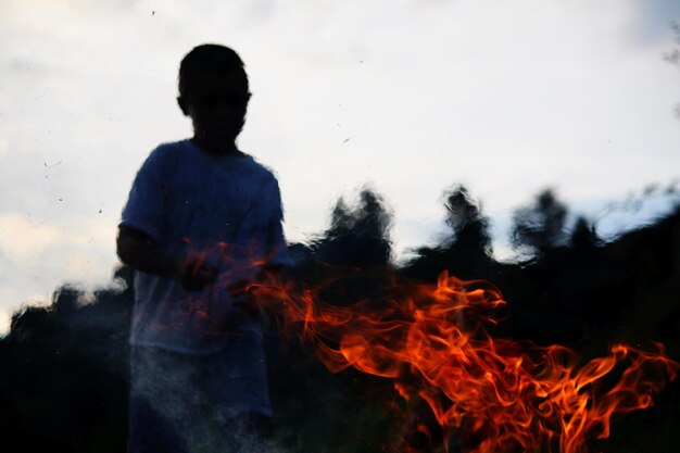 Foto junge steht am lagerfeuer gegen den himmel