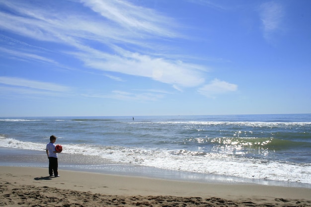Junge steht am Ufer gegen Meer und Himmel