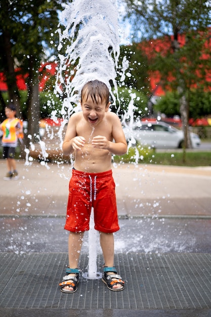 Junge steht im Brunnen viel Spritzer das Kind lacht eine fröhliche glückliche Kindheit