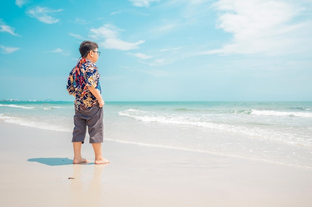 Junge steht im Sommer am Strand und genießt die Aussicht