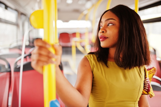 Junge stilvolle Afroamerikanerfrau, die auf einem Bus reitet.