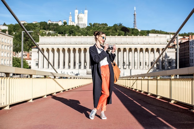 Junge stilvolle Frau mit Fotokamera auf der Fußgängerbrücke in der Altstadt von Lyon, Frankreich