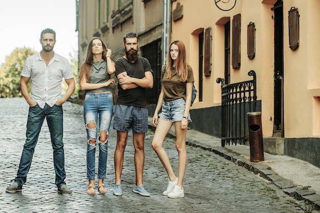 Junge, stilvolle, modische Freunde, die auf einer Ziegelstraße stehen