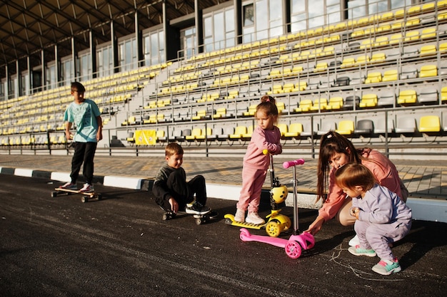 Junge stilvolle Mutter mit vier Kindern im Freien Sportfamilie verbringt Freizeit im Freien mit Rollern und Schlittschuhen Mit Kreide auf dem Asphalt gemalt