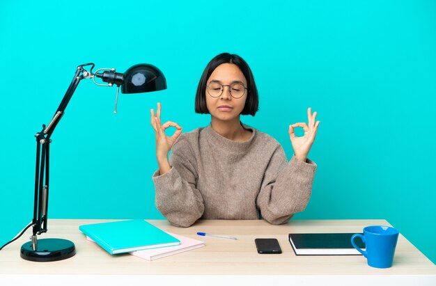 Junge Student gemischte Rasse Frau, die auf einem Tisch in Zen-Pose studiert