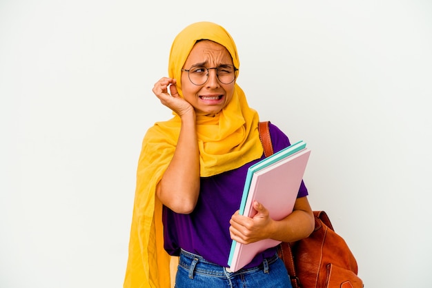 Junge Student muslimische Frau, die einen Hijab lokalisiert auf weißem Hintergrund trägt, der Ohren mit Händen bedeckt.