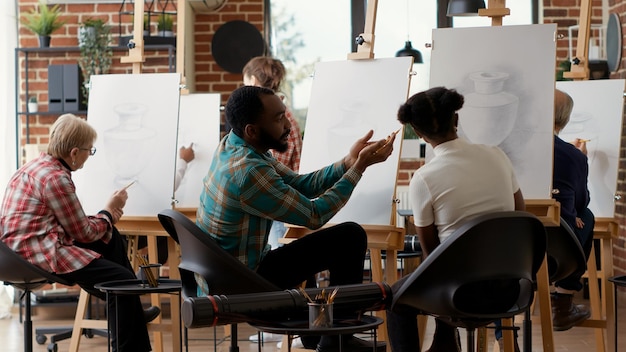 Junge Studenten zeichnen auf Leinwand und sprechen in künstlerischen Workshops über Kunstwerke, machen Skizzenübungen, um neue kreative Fähigkeiten zu erlernen. Besuch der Lehrklasse zum Zeichnen von Vasen. Stativaufnahme.