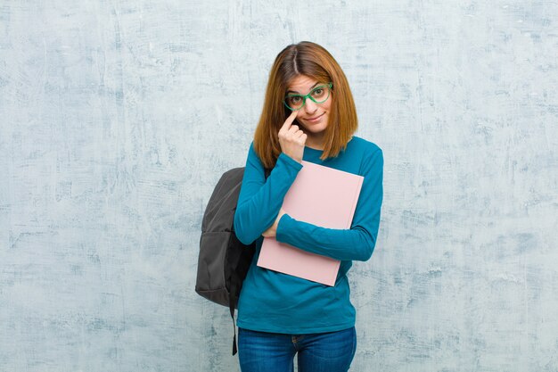 Junge Studentenfrau, die ein Auge auf Sie hält, nicht vertraut, wachsam und wachsam bleibt