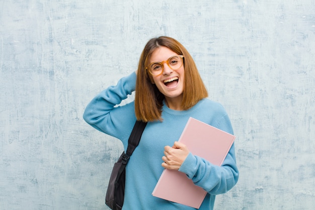 Junge Studentenfrau, die glücklich, sorglos, freundlich und entspannt schaut, das Leben und den Erfolg, mit einer positiven Haltung auf Schmutzwand genießend