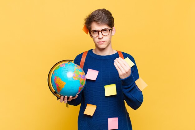 Junge Studentenjunge, die Capice oder Geldgeste macht und Ihnen sagt, dass Sie Ihre Schulden bezahlen sollen!