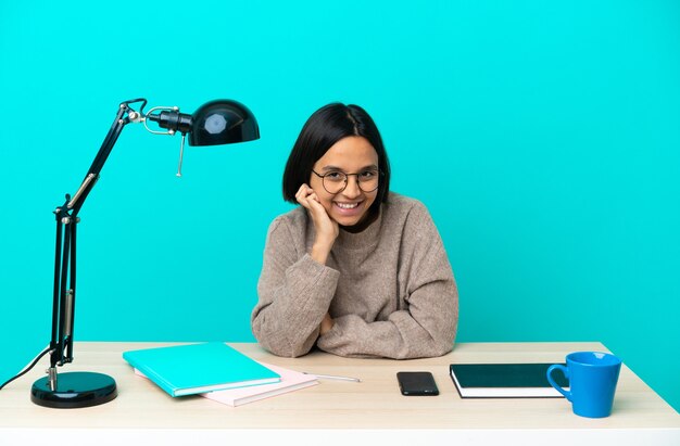 Junge Studentin der gemischten Rasse, die auf einem lachenden Tisch studiert