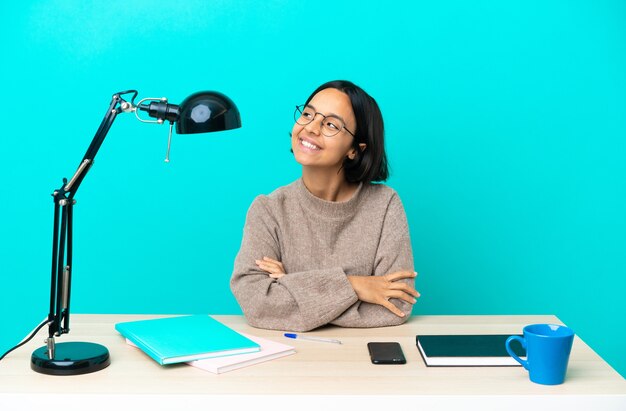 Junge Studentin der gemischten Rasse, die auf einem Tisch studiert und eine Idee denkt, während sie aufschaut