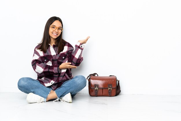 Junge Studentin, die auf dem Boden sitzt und Hände zur Seite ausdehnt