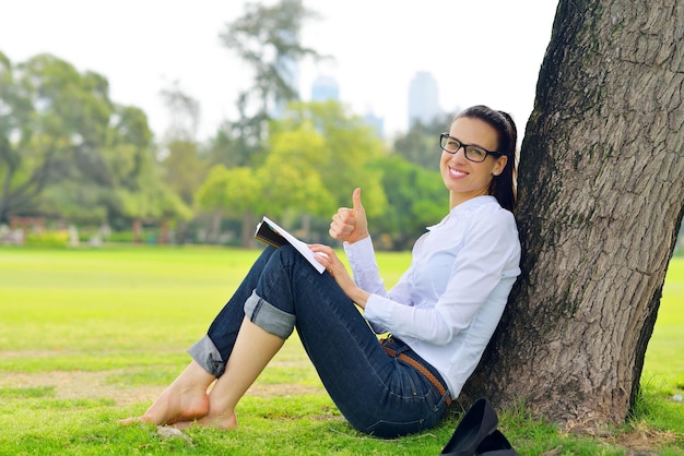 Junge Studentin, die ein Buch liest und im Park studiert