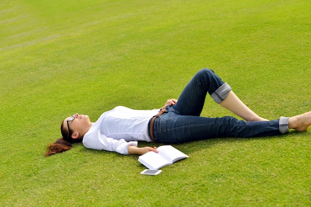 Junge Studentin, die ein Buch liest und im Park studiert