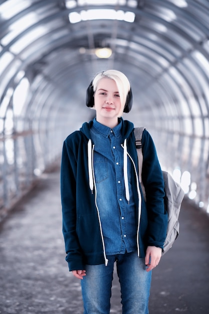 Junge Studentin, die Musik in großen Kopfhörern im U-Bahn-Tunnel hört