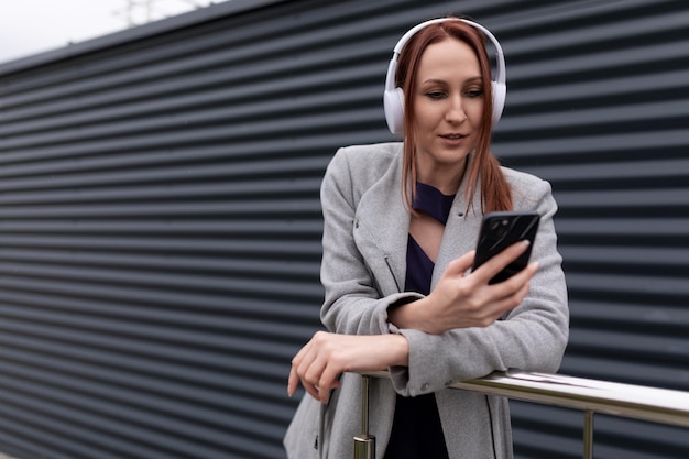 Junge Studentin, die sich auf einer Stadtstraße eine Playlist über Kopfhörer anhört