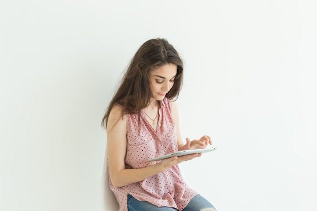 Junge Studentin, die Tablette auf weißer Wand verwendet