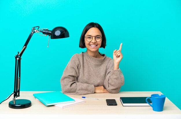 Junge Studentin gemischter Abstammung, die einen Tisch studiert und eine großartige Idee aufzeigt