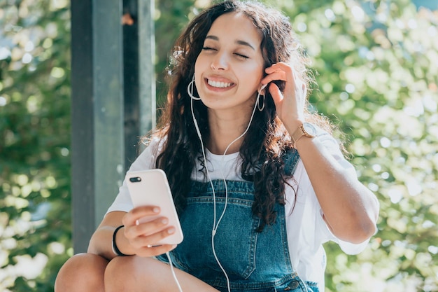 Junge Studentin hört Musik auf seinem Telefon an der Universität, Kopierraum, sonniger Tag, Hipster-Stil