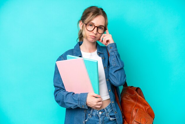 Foto junge studentin, isoliert auf blauem hintergrund, denkt an eine idee