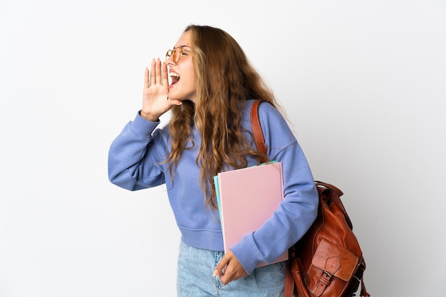 Junge Studentin lokalisiert auf weißem Hintergrund, der mit dem Mund weit offen zur Seite schreit