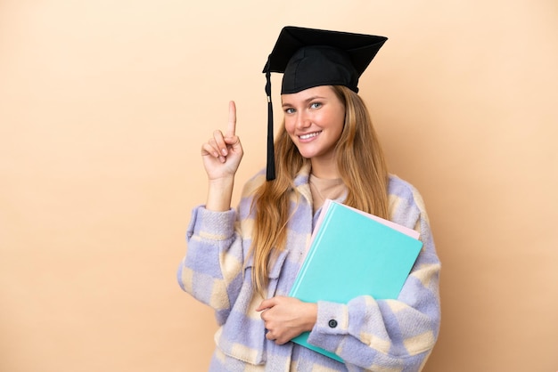 Junge Studentin mit isoliertem Hintergrund, die einen Finger im Zeichen der Besten zeigt und hebt