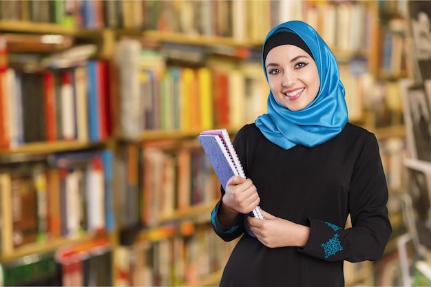 Junge Studentin mit Notebook in der Bibliothek