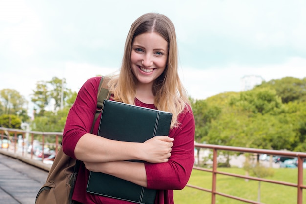 Junge Studentin mit Ordnern im Collegecampus.