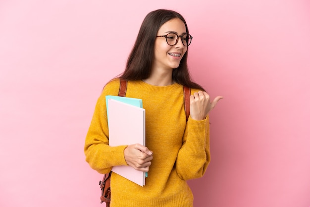 Junge Studentin über isoliertem Hintergrund, der zur Seite zeigt, um ein Produkt zu präsentieren