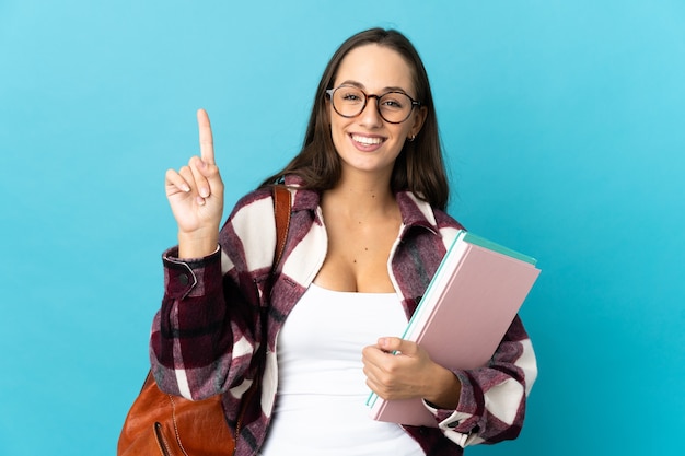 Junge Studentin über isoliertem Hintergrund, die einen Finger im Zeichen des Besten zeigt und hebt