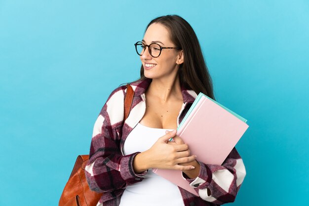 Junge Studentin über isoliertem Hintergrund, die Seite schaut