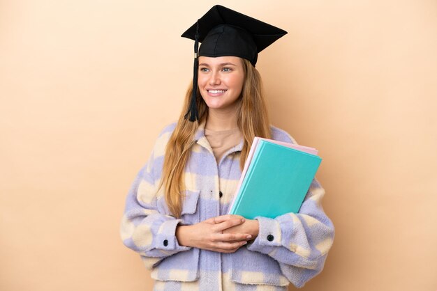 Junge Studentin über isoliertem Hintergrund, die zur Seite schaut