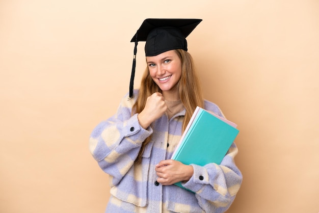 Junge Studentin vor isoliertem Hintergrund, die einen Sieg feiert