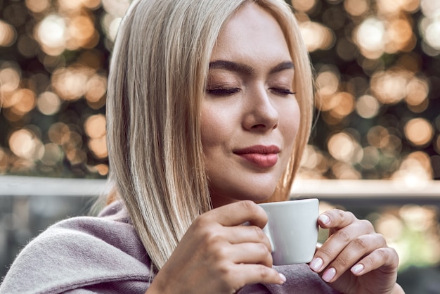 Junge stylische Blondine genießt Kaffee