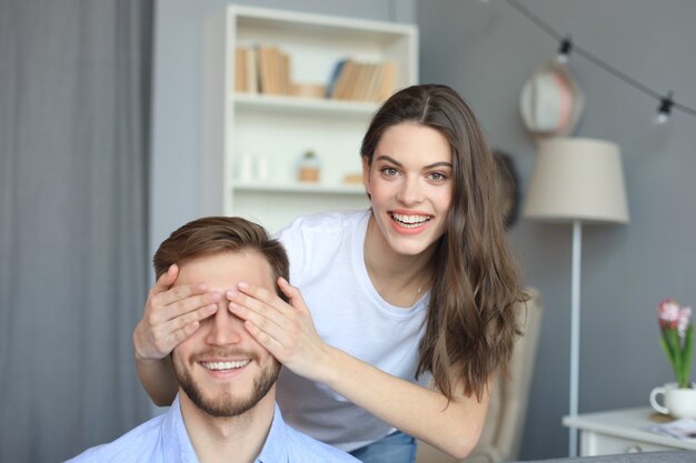 Junge süße Frau, die die Augen ihres Mannes bedeckt.