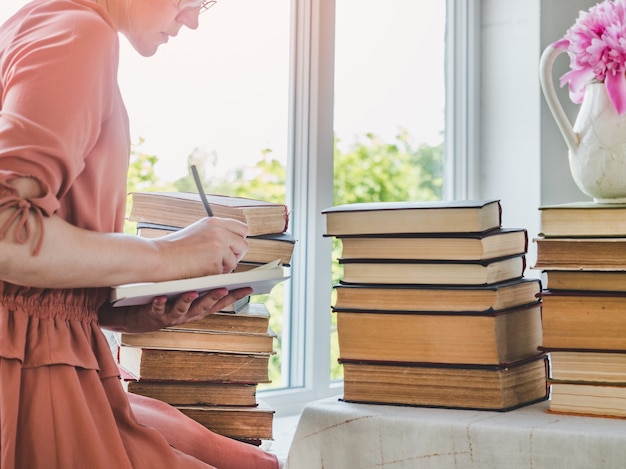 Junge, süße Frau und Stapel von Vintage-Büchern