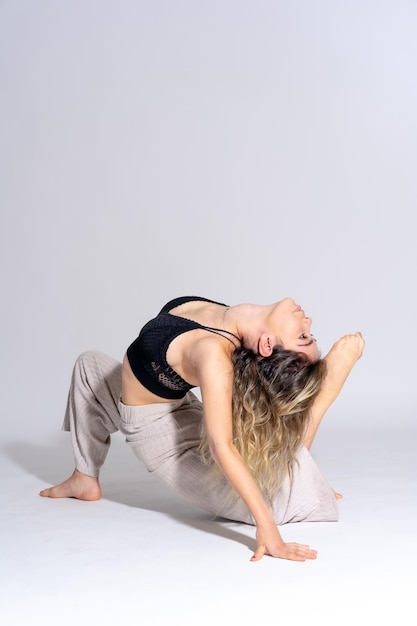 Junge Tänzerin in einer Studio-Fotosession mit einem weißen Hintergrundballerina-Ballett, das Übungen auf dem Boden durchführt