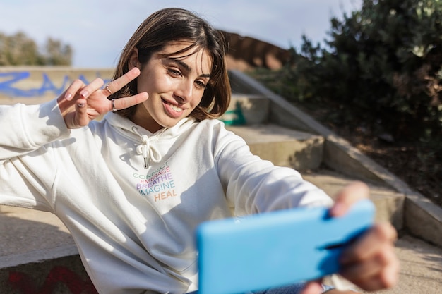 Junge tausendjährige Frau, die im Freien in der Stadt selfie mit dem Handy nimmt