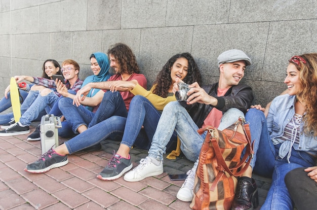 Foto junge tausendjährige freunde, die spaß am chatten haben, fotos mit einer vintage-kamera machen und smartphones verwenden - jugend, generation z, technologietrends und vielpunktiges konzept - hauptaugenmerk auf das gesicht des richtigen mannes