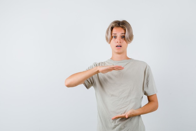 Junge Teenager-Junge mit großem Schild im T-Shirt und verwirrt suchen. Vorderansicht.