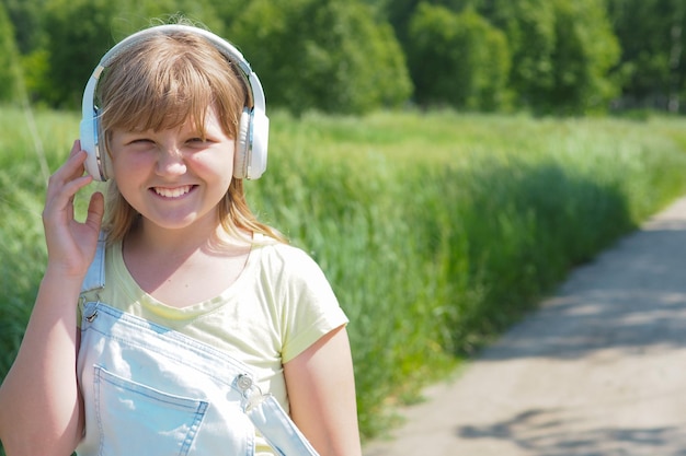 Junge Teenagerin geht mit Kopfhörern im Park und lacht.