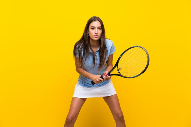 Junge Tennisspielerfrau über lokalisierter gelber Wand